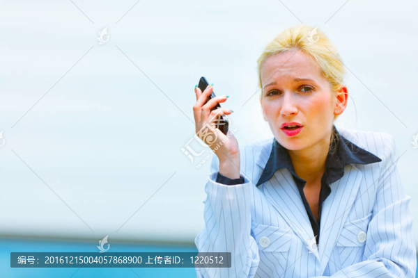 憤怒的現(xiàn)代商業(yè)女性用手機(jī)倚在辦公樓欄桿上