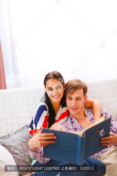 快樂的年輕夫婦坐在沙發(fā)上看相冊