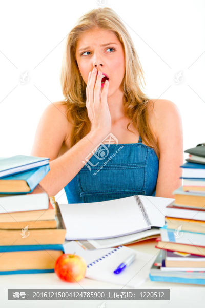 震驚的少女坐在書桌旁堆著書
