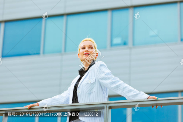 現(xiàn)代商業(yè)的女人微笑著扶著欄桿在辦公樓看著分隔開的