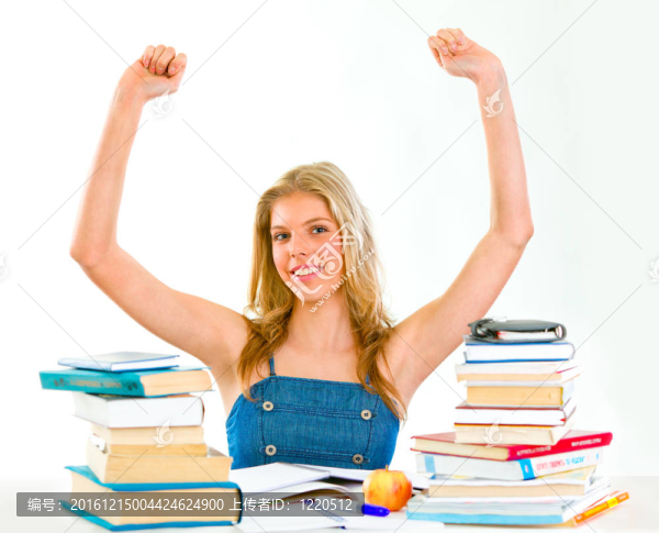 高興的女孩坐在桌子上與書舉起手