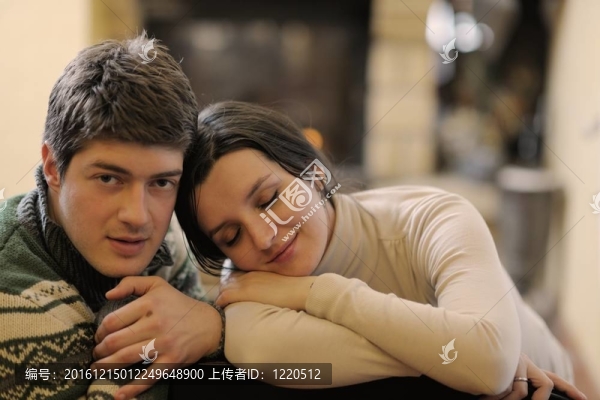 快樂的年輕情侶坐在家里壁爐前的沙發(fā)上