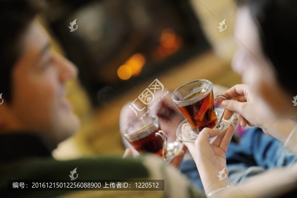快樂的年輕情侶坐在家里壁爐前的沙發(fā)上