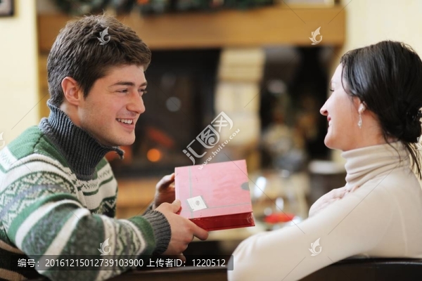 快樂(lè)的年輕情侶坐在家里壁爐前的沙發(fā)上