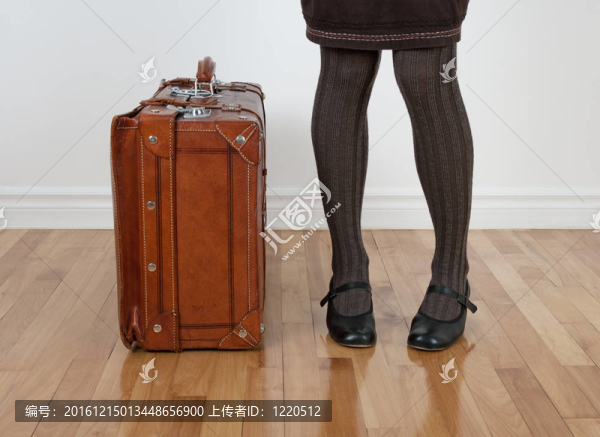 穿著棕色長襪的女人站在老式手提箱旁邊