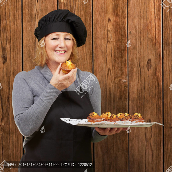 中年女人抱著對(duì)做木墻自制的松餅的肖像