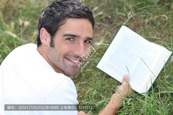 一個(gè)男人躺在草地上讀一本書(shū)