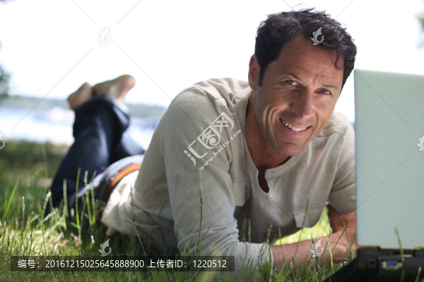 男人微笑工作在草地上