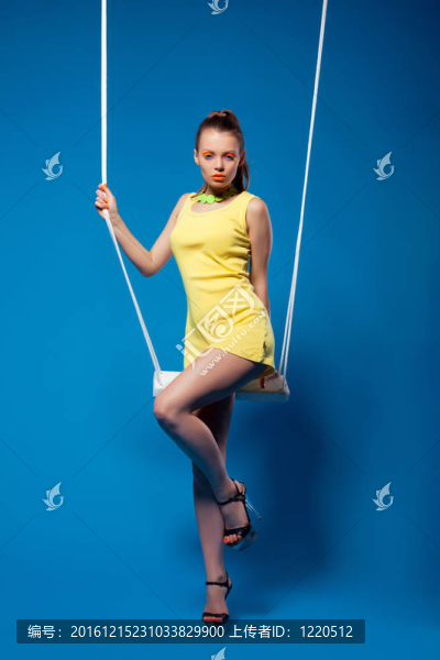 性感的女人在黃色的秋千與明亮的化妝