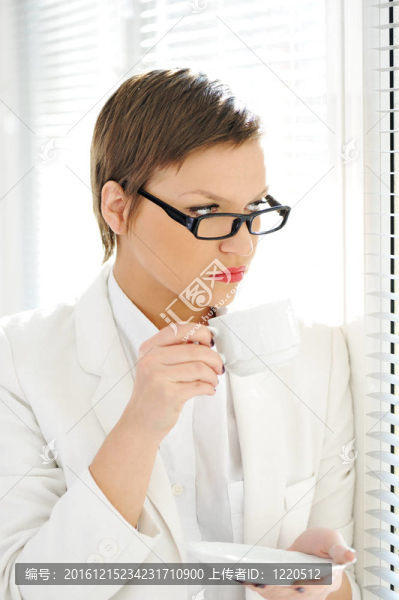 年輕的商業(yè)婦女一邊喝咖啡一邊看著窗外