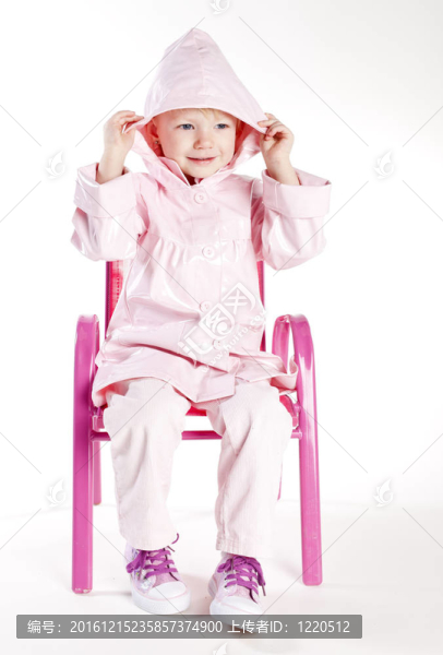 小女孩穿著雨衣坐在椅子上