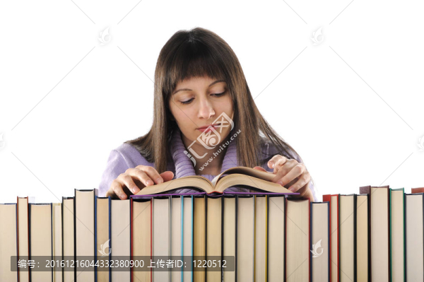 年輕婦女在一大堆書后面讀一本書