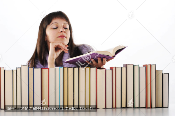 年輕婦女在一大堆書后面讀一本書