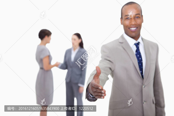 微笑的商人在白人背景下與他身后握手的同事們握手
