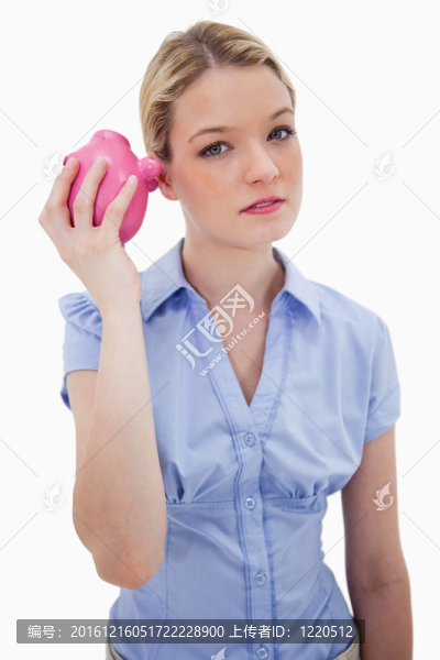 女人好奇地?fù)u著小豬存錢罐