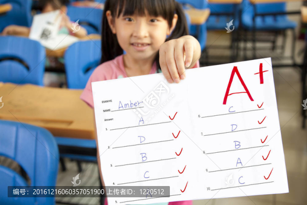 微笑的小女孩在教室里拿著試卷