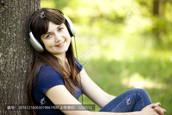 年輕時尚女孩帶著耳機在綠春草。