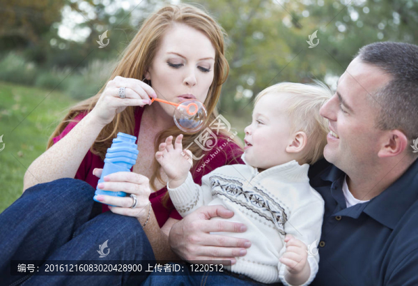 年輕的父母在Park和他們的孩子吹泡泡