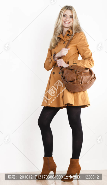 站著的女人穿著外套和時髦的棕色鞋子和手提包