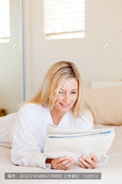 漂亮的年輕女人在床上看報紙