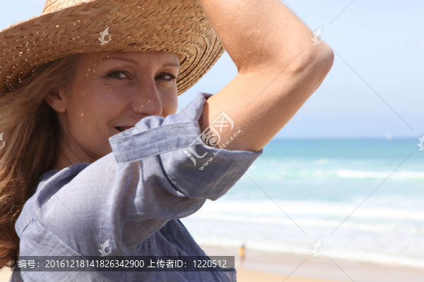 微風中抱著草帽的女人