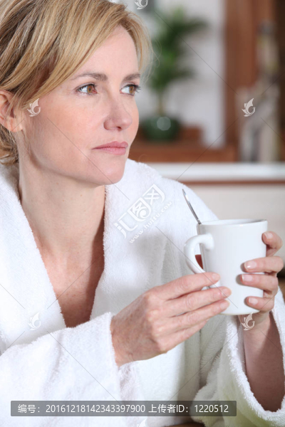 穿著浴袍在早上喝一杯咖啡沉思的女人