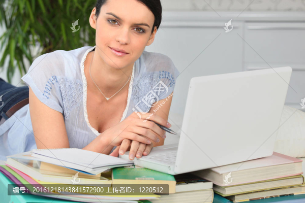 有一堆書和一臺(tái)筆記本電腦的學(xué)生