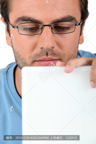 戴眼鏡的人盯著他的筆記本電腦