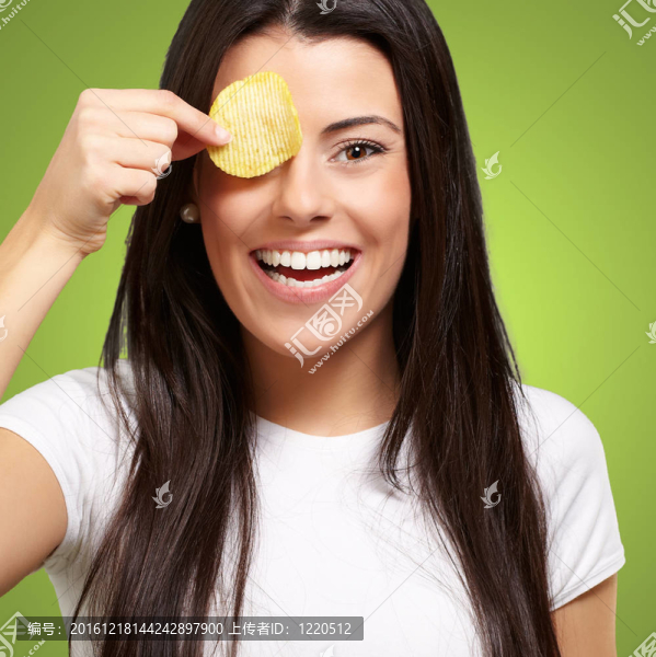 年輕女子舉著土豆片在她眼前看著綠色的肖像