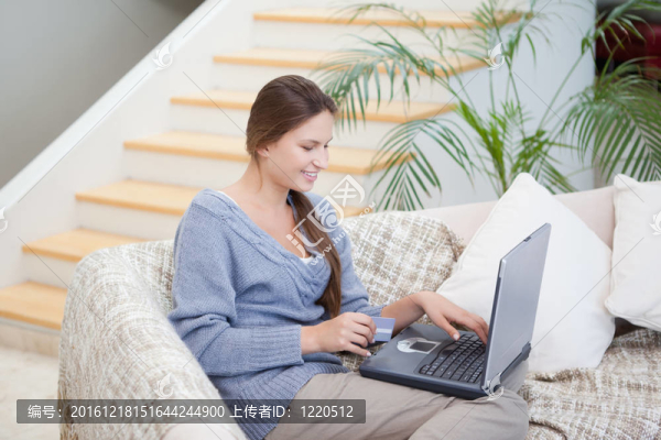 用筆記本坐在沙發(fā)上的女人