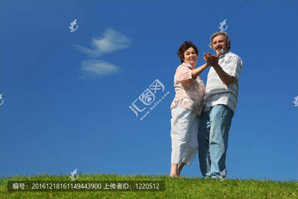 在夏天的草坪上跳舞的老婦人和男人；藍(lán)天