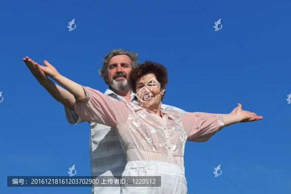 老人和女人站在一起；微笑著看著相機(jī)；手分開；藍(lán)天