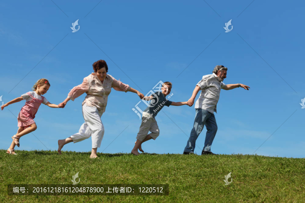 孫子和他們的祖父母在草地上奔跑，手牽著手