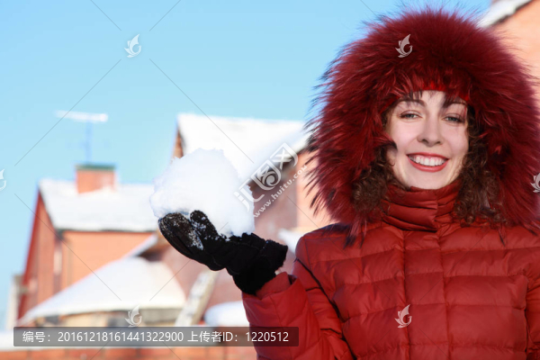 穿著紅色夾克的漂亮女人在冬天保持著雪和微笑
