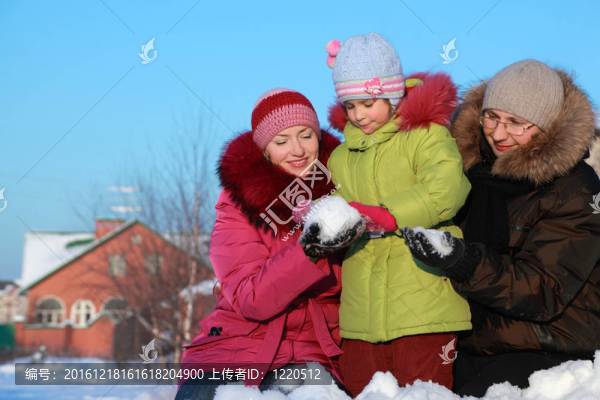 爸爸媽媽在冬天給女兒在戶外做雪球