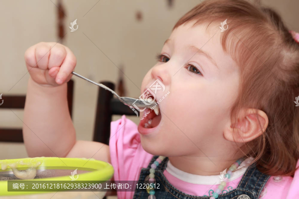 漂亮的小女孩穿著粉色襯衫吃稀飯；黃色盤子