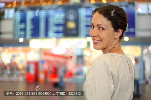 美麗的年輕女子穿著白色的衣服在機(jī)場(chǎng)大廳；她微笑