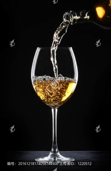 將白葡萄酒倒入黑色背景的玻璃杯