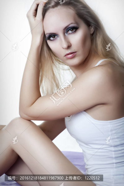 美麗年輕性感女人穿著白色內(nèi)衣坐在床上