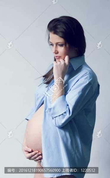 美麗的微笑孕婦懷著藍色的襯衫。長黑發(fā)。手放肚子。妊娠的收集。
