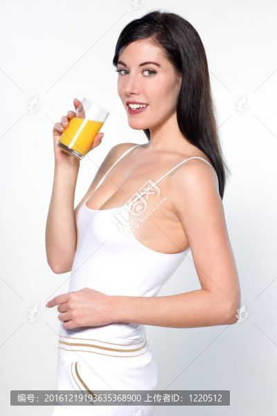美麗的年輕女子喝橙汁在工作室白色孤立的背景