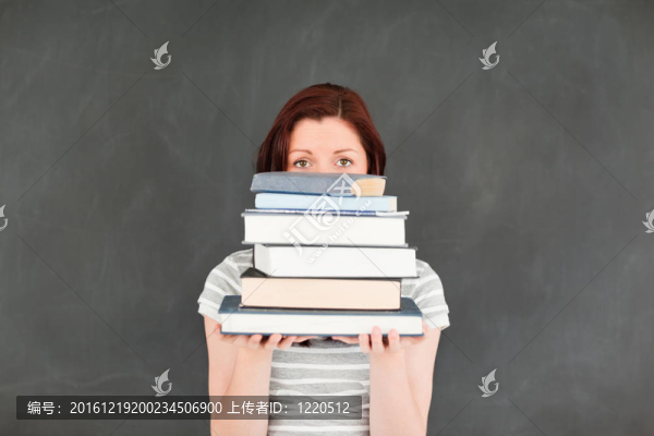 可愛的年輕女人躲在一堆書后面