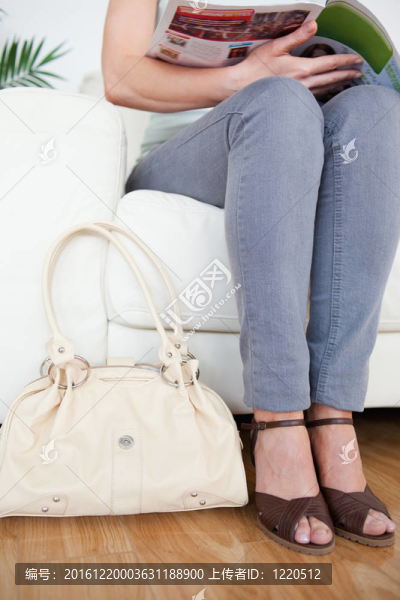 一個(gè)漂亮的女人在沙發(fā)上的一個(gè)袋子和一個(gè)雜志在候診室