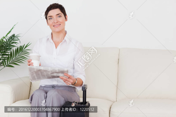 帶著手提箱的短發(fā)女人；在候車室里的報(bào)紙和杯子