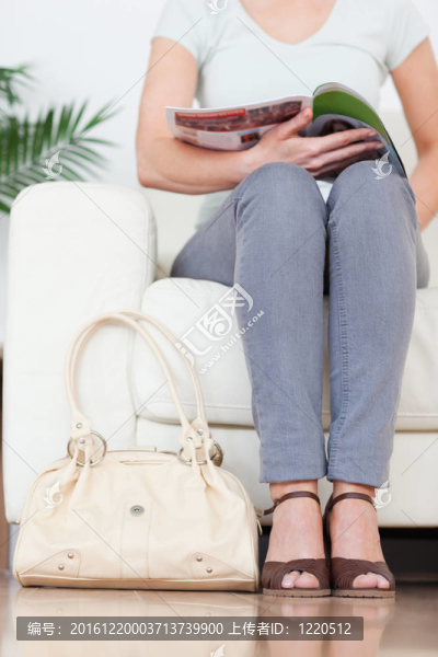 一個(gè)可愛(ài)的女人在沙發(fā)上帶著一個(gè)袋子和一本雜志