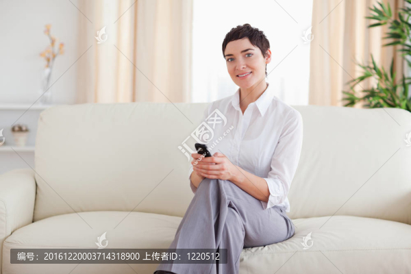 可愛的女人坐在沙發(fā)上打電話
