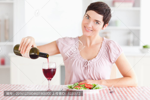 在玻璃杯里倒紅酒的女人
