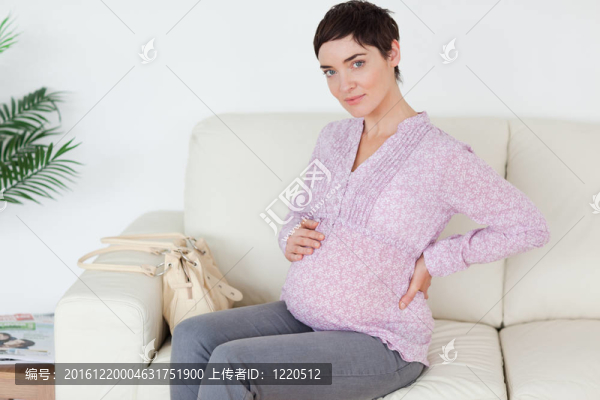 美麗的孕婦坐在沙發(fā)上摸她的肚子