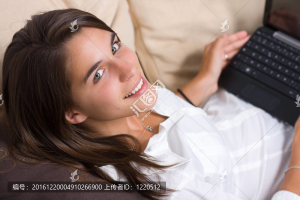 漂亮的年輕女人在沙發(fā)上使用筆記本電腦