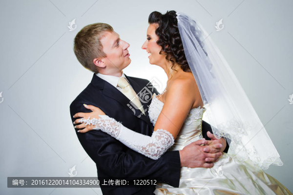 年輕優(yōu)雅的迷戀剛結婚的新娘和新郎要互相擁抱灰色背景工作室肖像